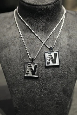 Two sizes of a custom N tag pendant, worn layered